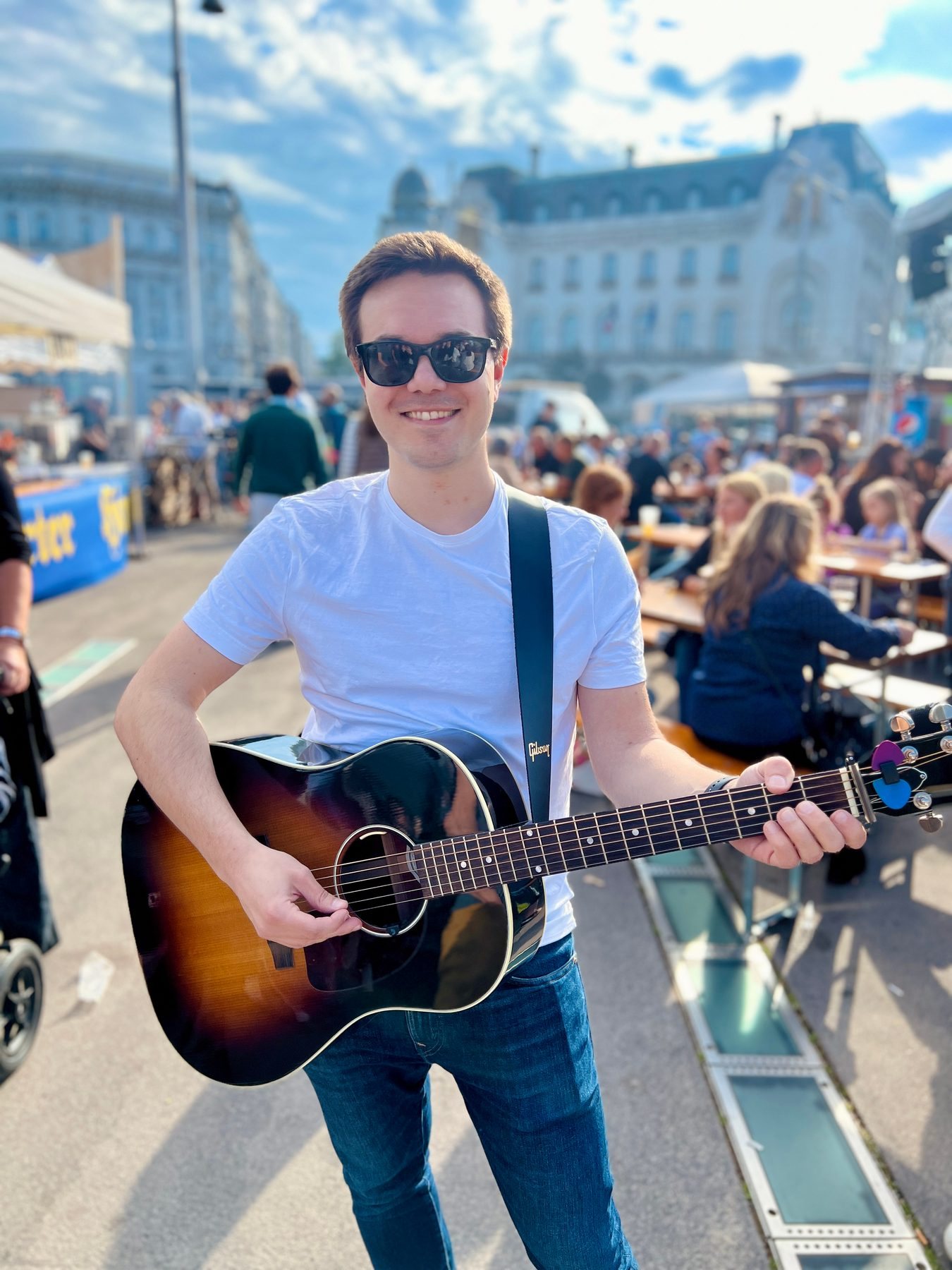 Simon Schütt mit Akustikgitarre am Mikrofon bei einer Feier im Freien, Schwarzweißaufnahme